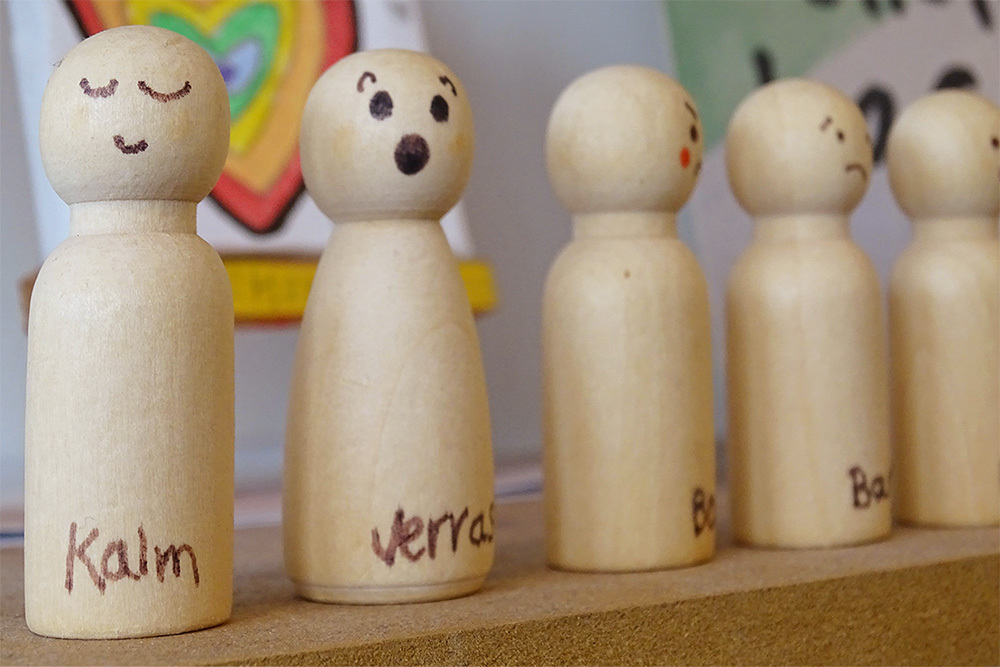 Een rijtje houten poppetjes die verschillende emoties uitbeelden